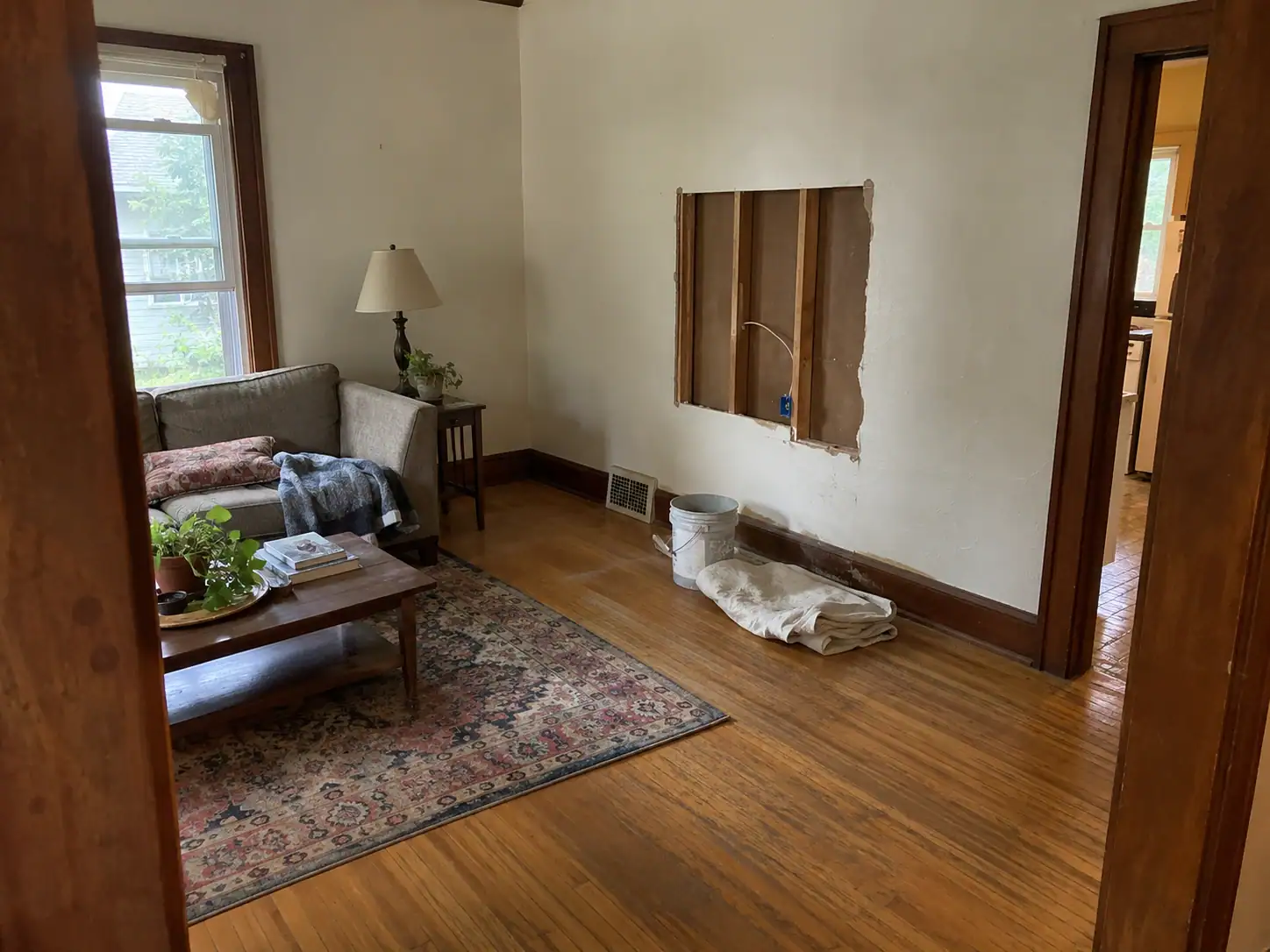 Living room with worn wood flooring and an unfinished drywall repair